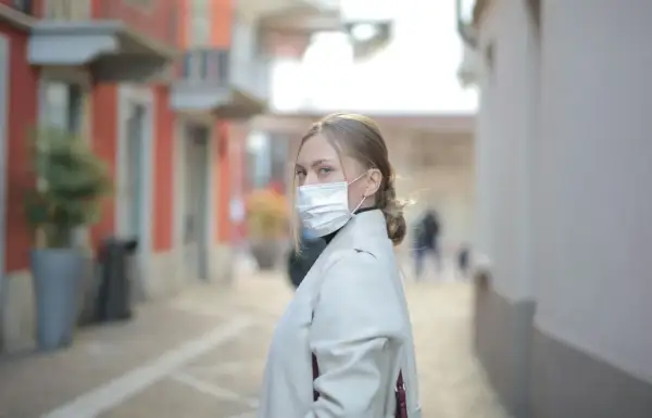 Kobieta w masce na twarzy, zastanawia się, ile można być na L4, idąc ulicą.